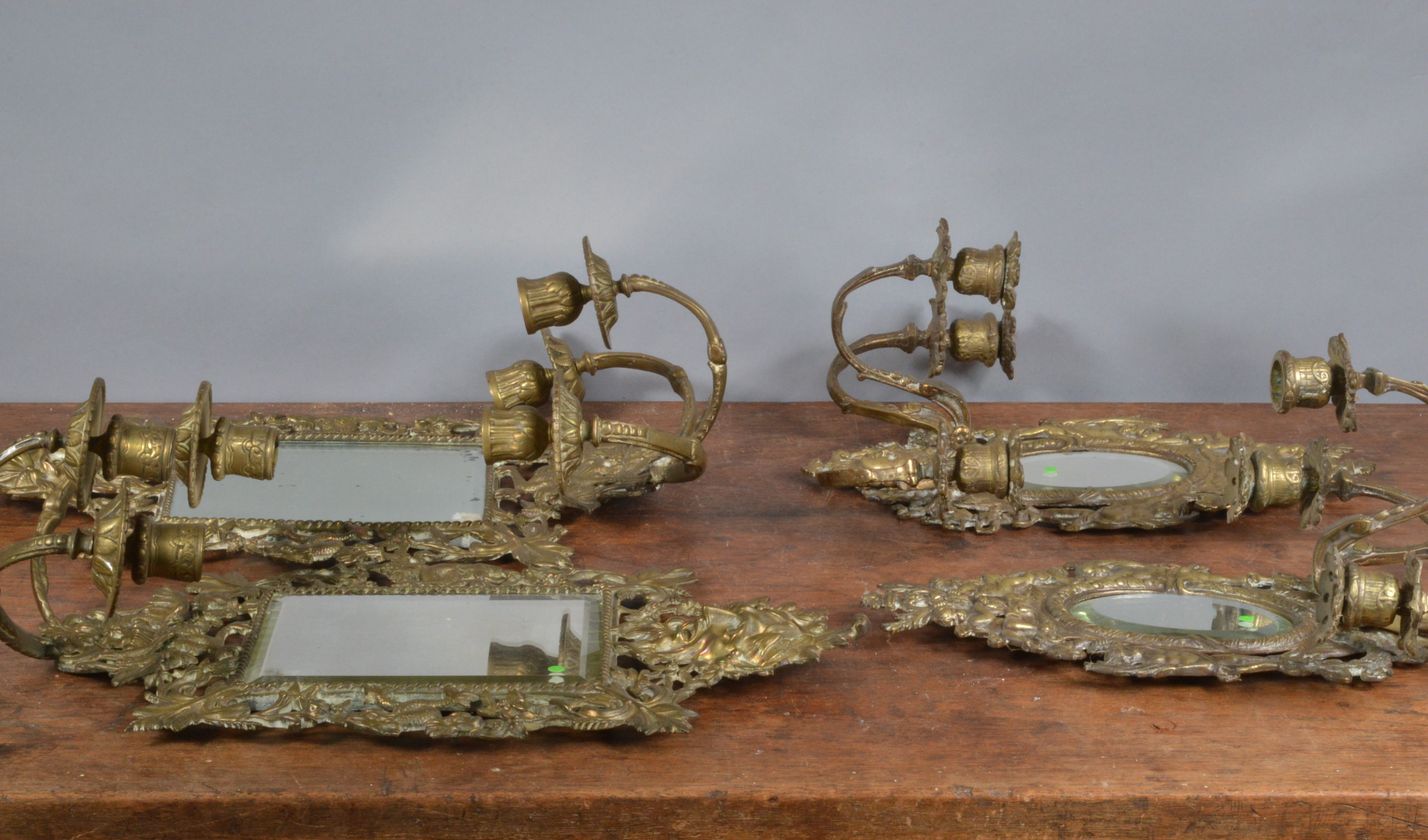 Two pairs of early 20th century mirrored brass wall sconces, each with three branches, one