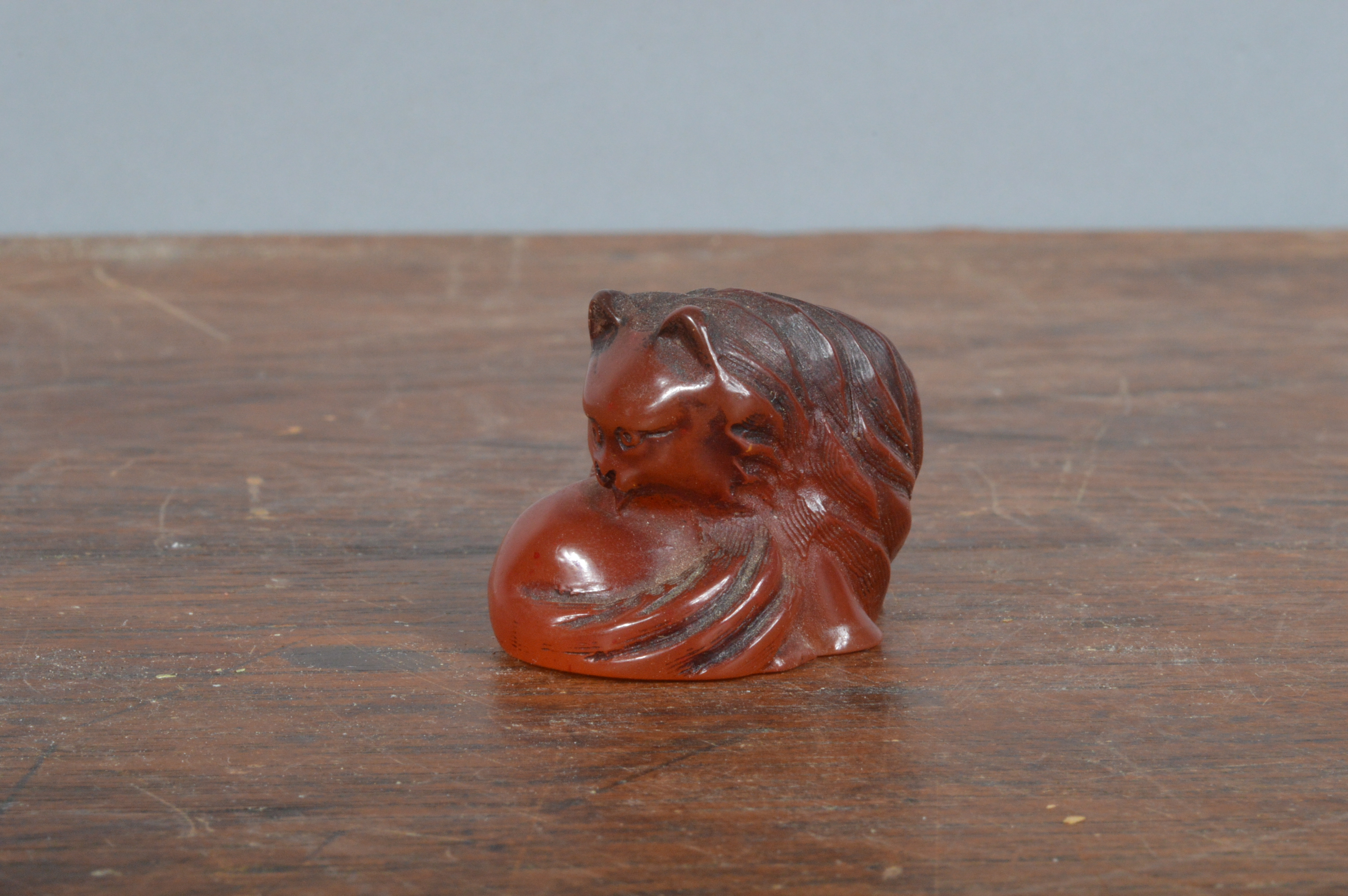 A late Meji period hand-carved Japanese netsuke, of Amber depicting a cat. 3.5 cm long. (1)
