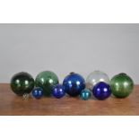 A collection of coloured 19th century and later glass fishing floats, blue, green and clear glass,