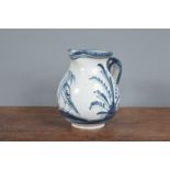A 19th century French faience jug, decorated in blue with a design of a bird and flowers. Crack from