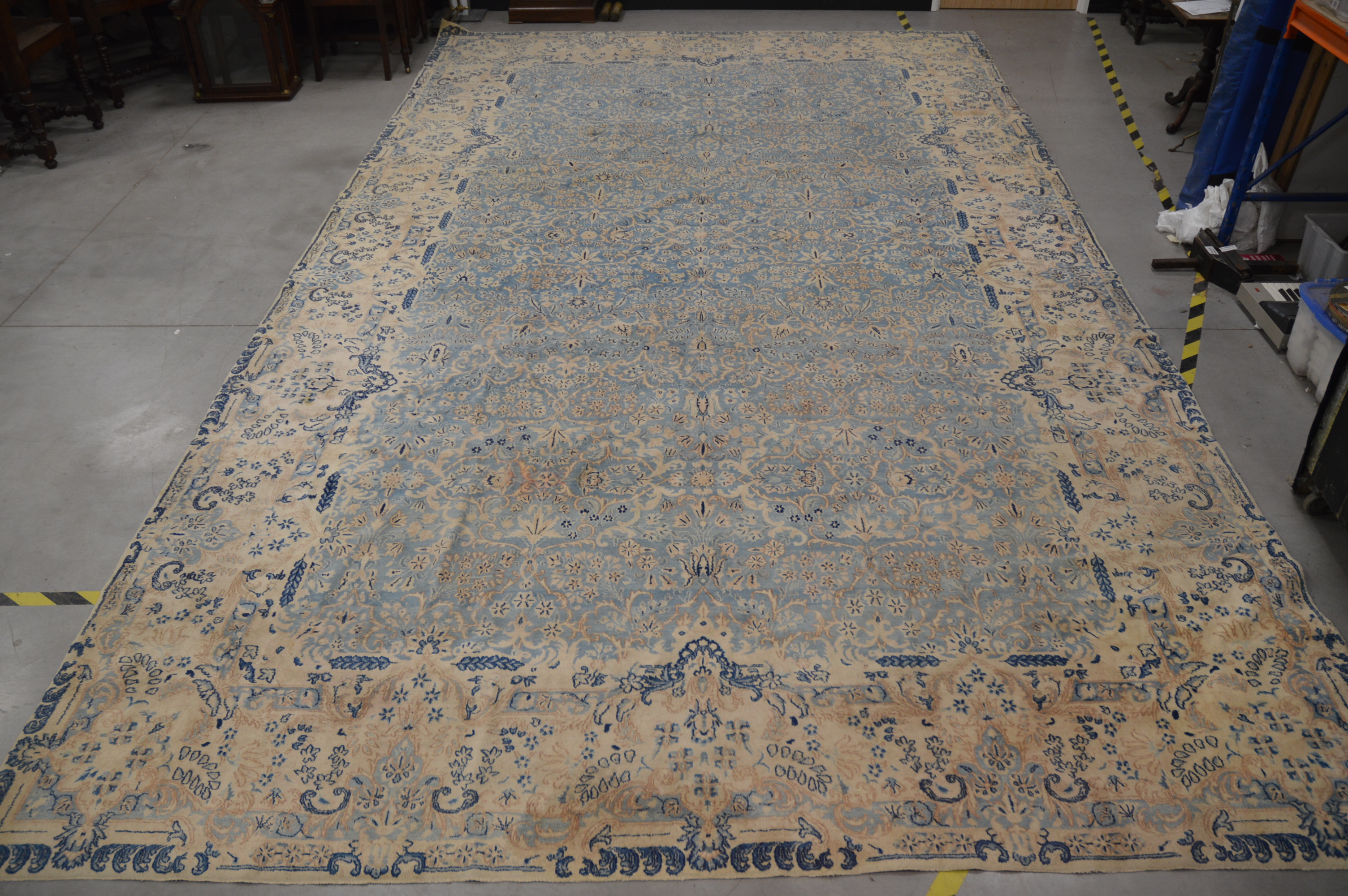A very large Modern wool carpet, blue central ground with ivory border, some staining and moth