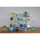 A large collection of glass paperweights, including examples by Mdina, some millefiori, of