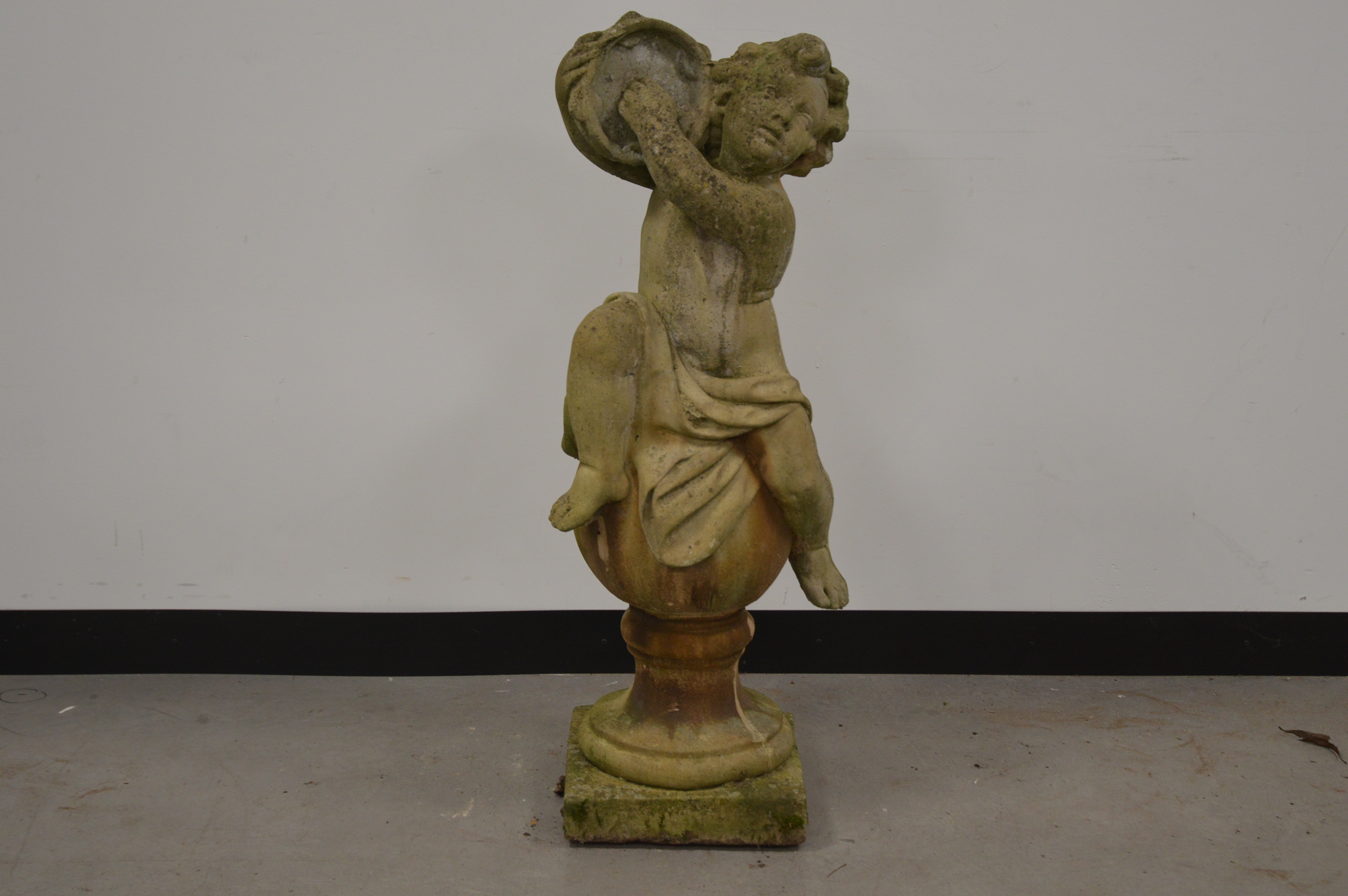 A cast garden figure of a cherub, playing a tambourine. 101 cm tall. Some wear and weathering. AF (