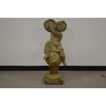 A cast garden figure of a cherub, playing a tambourine. 101 cm tall. Some wear and weathering. AF (