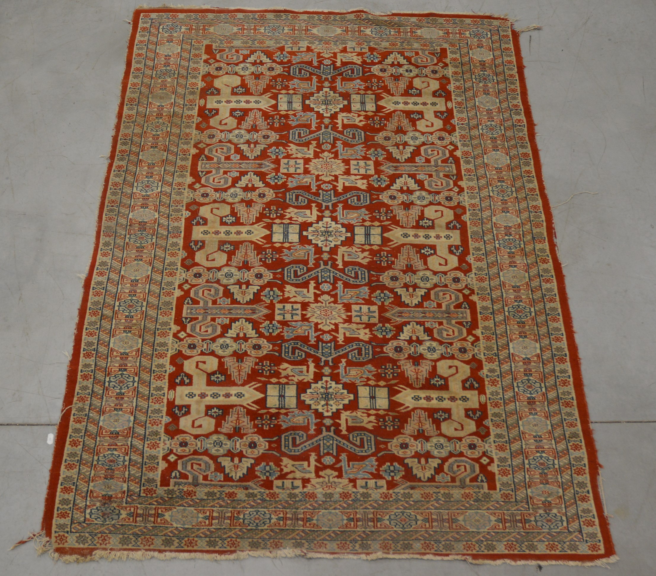 A Caucasian style wool on cotton rug, geometric design, faded and one corner with moth damage AF