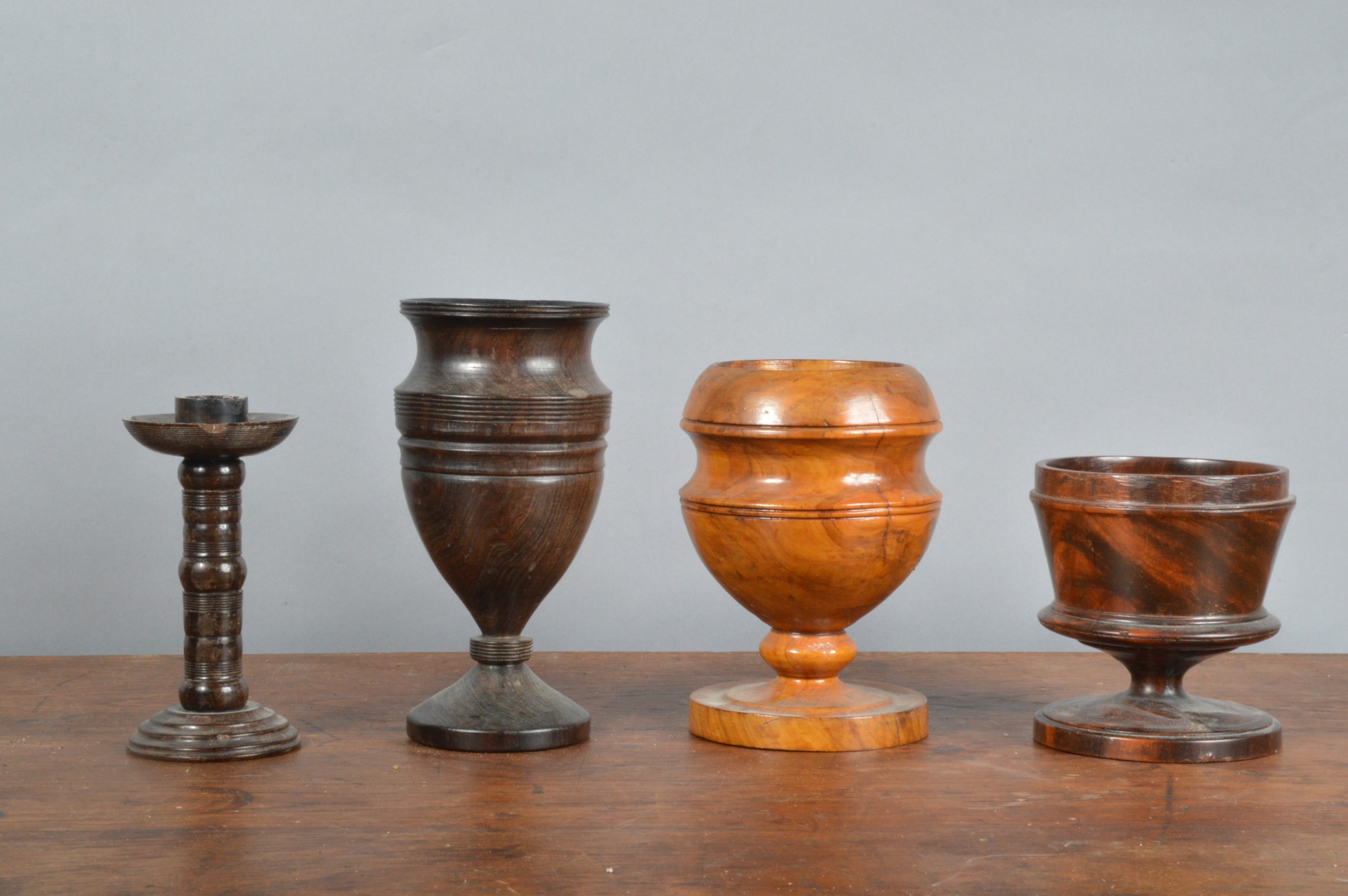 Four 19th century and later turned treen items, comprising a candlestick 15cm high, and three footed