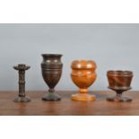 Four 19th century and later turned treen items, comprising a candlestick 15cm high, and three footed