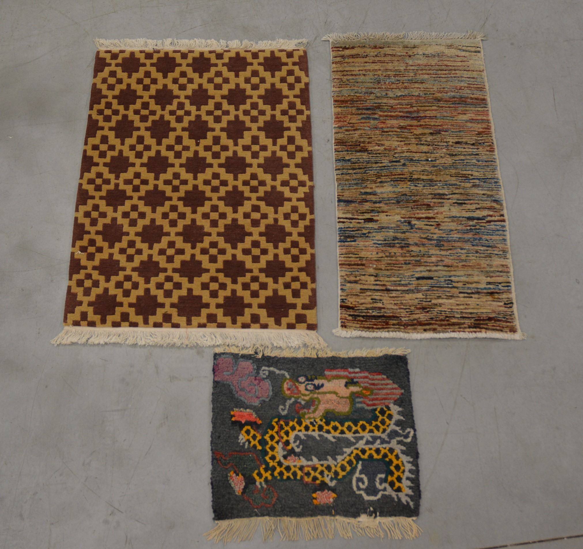 Three assorted rugs, comprising a geometric example 90cm x 62cm, and a striped example and