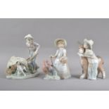 Three Lladro porcelain figural groups, comprising a boy with a wheelbarrow, 22cm high, a girl with