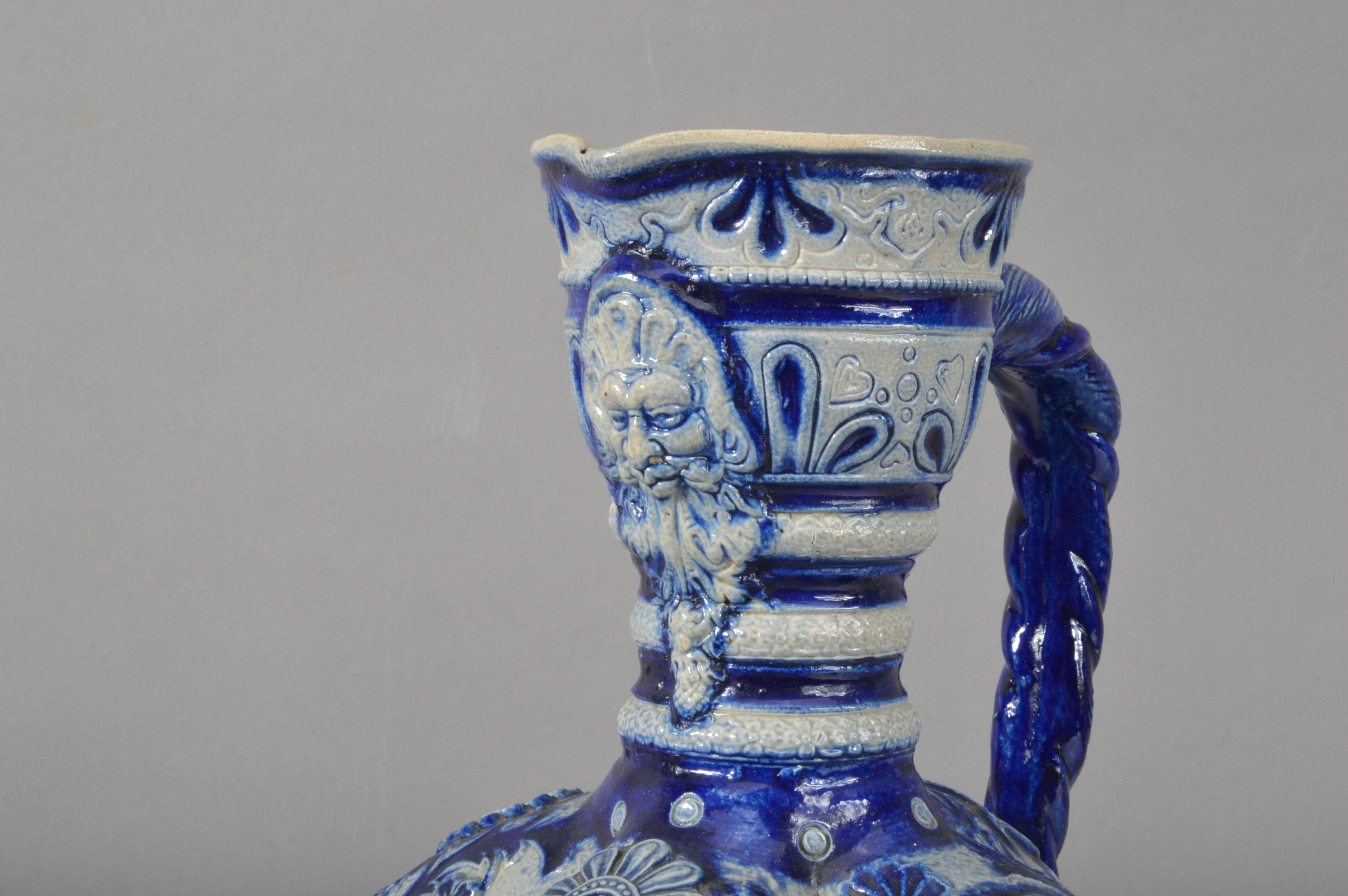 A German Westerwald salt-glazed stoneware ewer, blue and white raised decoration, a face below the - Image 3 of 5