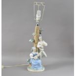 A Lladro porcelain table lamp, the column with two figures, the lady playing a lute on a