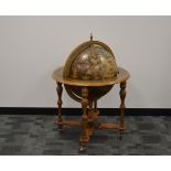 A modern drinks cabinet in the form of a globe, the exterior with peeling decoration, raised on