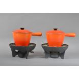 A pair of Le Creuset fondu pans and burners, orange glaze, both marked and with covers and