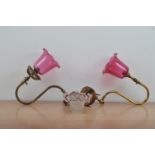 Two Victorian and later brass and cranberry glass wall lights, of differing sizes and condition,
