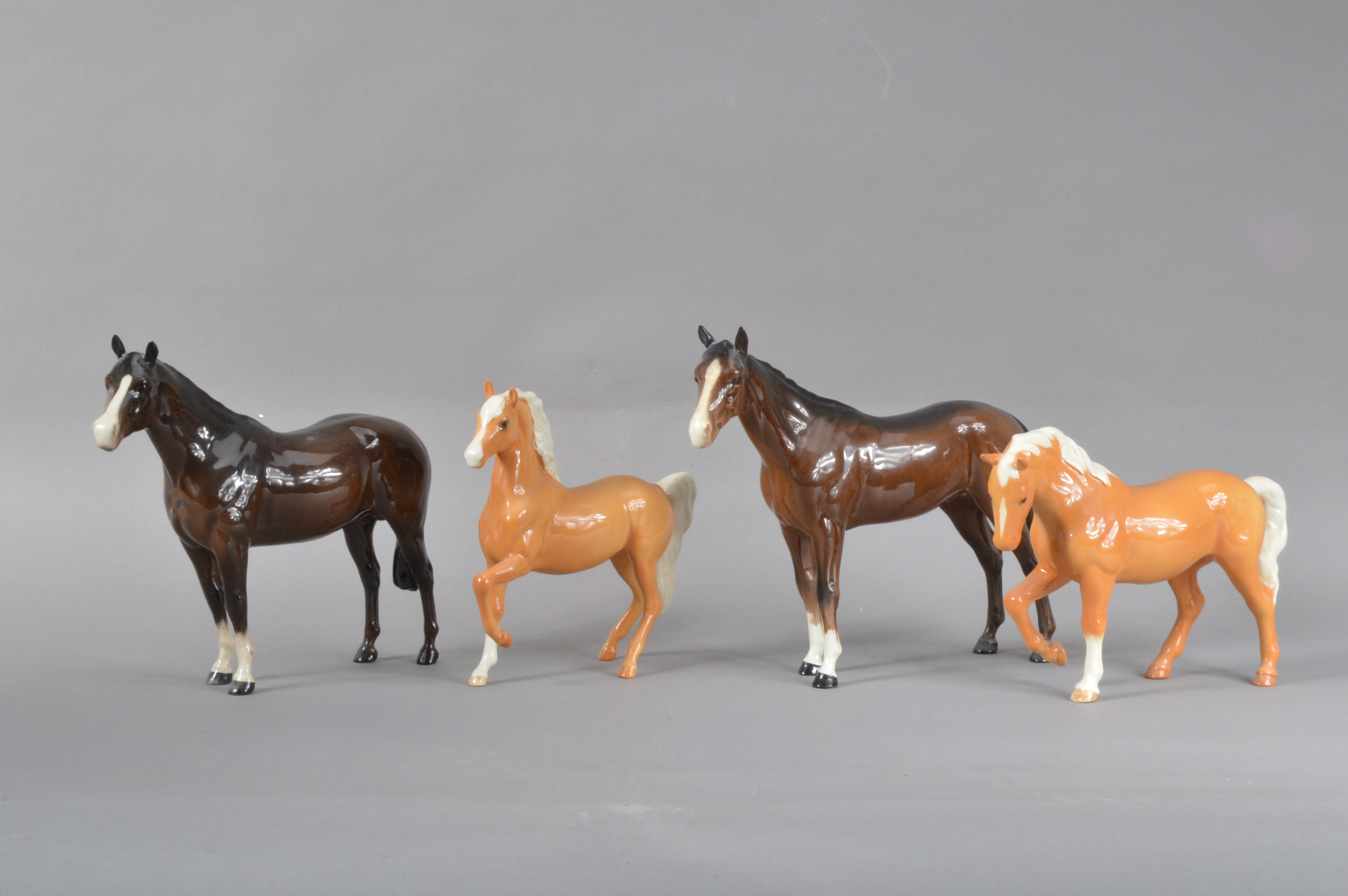 Four 20th century ceramic Beswick horses, two larger dark brown examples, the largest 21cm H x