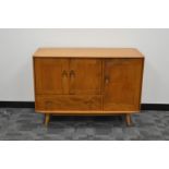 A 1960's/1970's elm Ercol sideboard, two cupboard doors above a drawer, with one large cupboard door