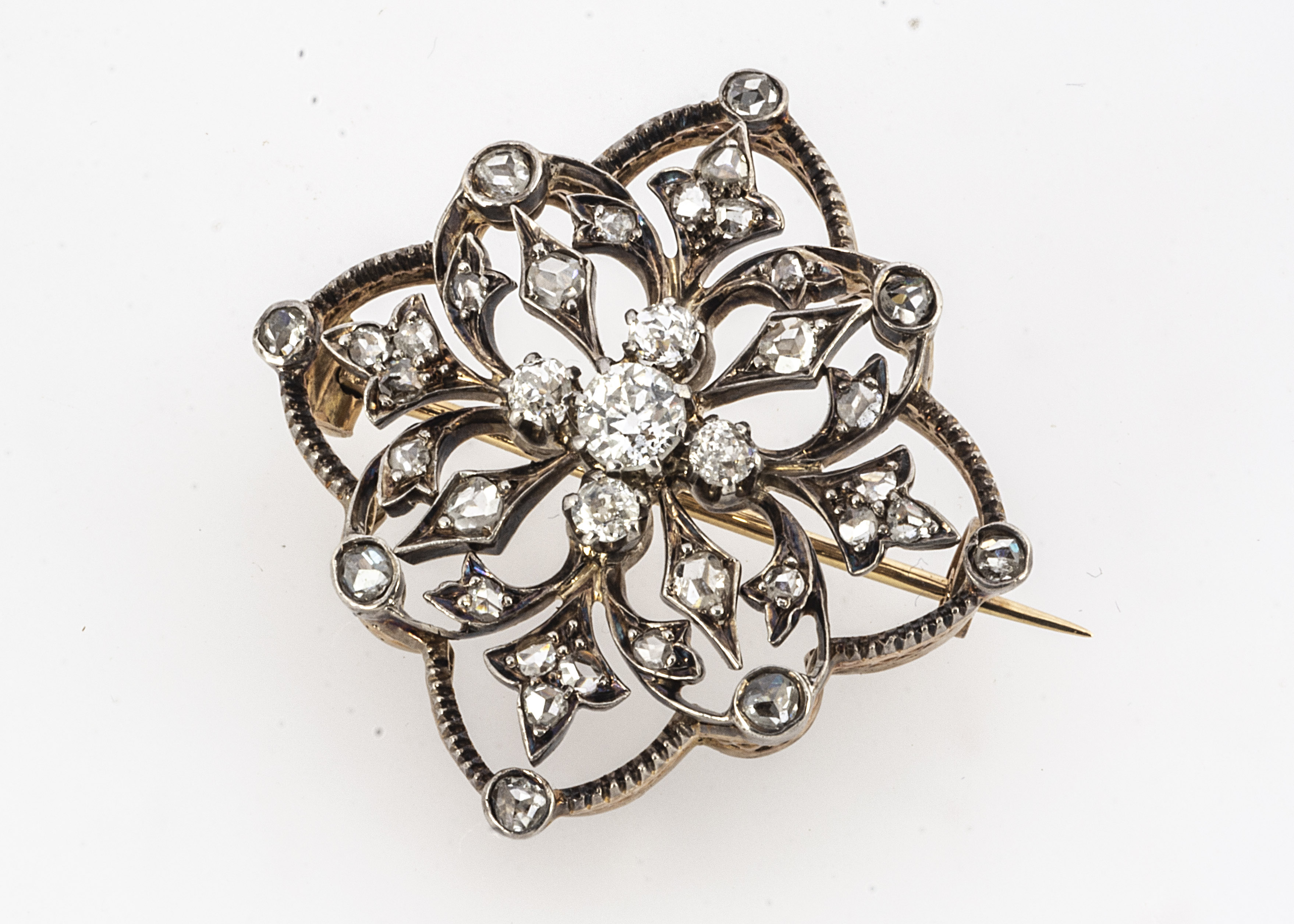 An early 20th century French open work brooch/pendant, of flower head design centred with an old cut