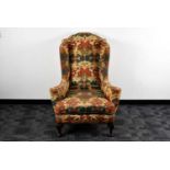An early 20th century upholstered wing back armchair,