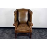 A George III style leather wing back armchair,