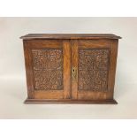 A Wooden smokers box with carved panel doors, pipe