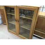 A Ercol display cabinet with a pair of glazed door