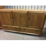 A Ercol sideboard fitted with three cupboards and