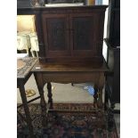 An oak cabinet table the top cabinet with carved cupboard doors on oak table with turned legs.