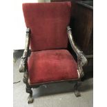 A large red velvet upholstered arm chair with carv