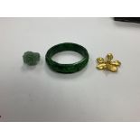 A green hard stone bangle, a rose ring and a yellow metal broach.