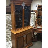 A light oak bookcase with a shaped pediment above