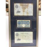 A frame containing three old bank notes comprising