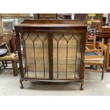 A glazed 1940s oak ball and claw footed display ca