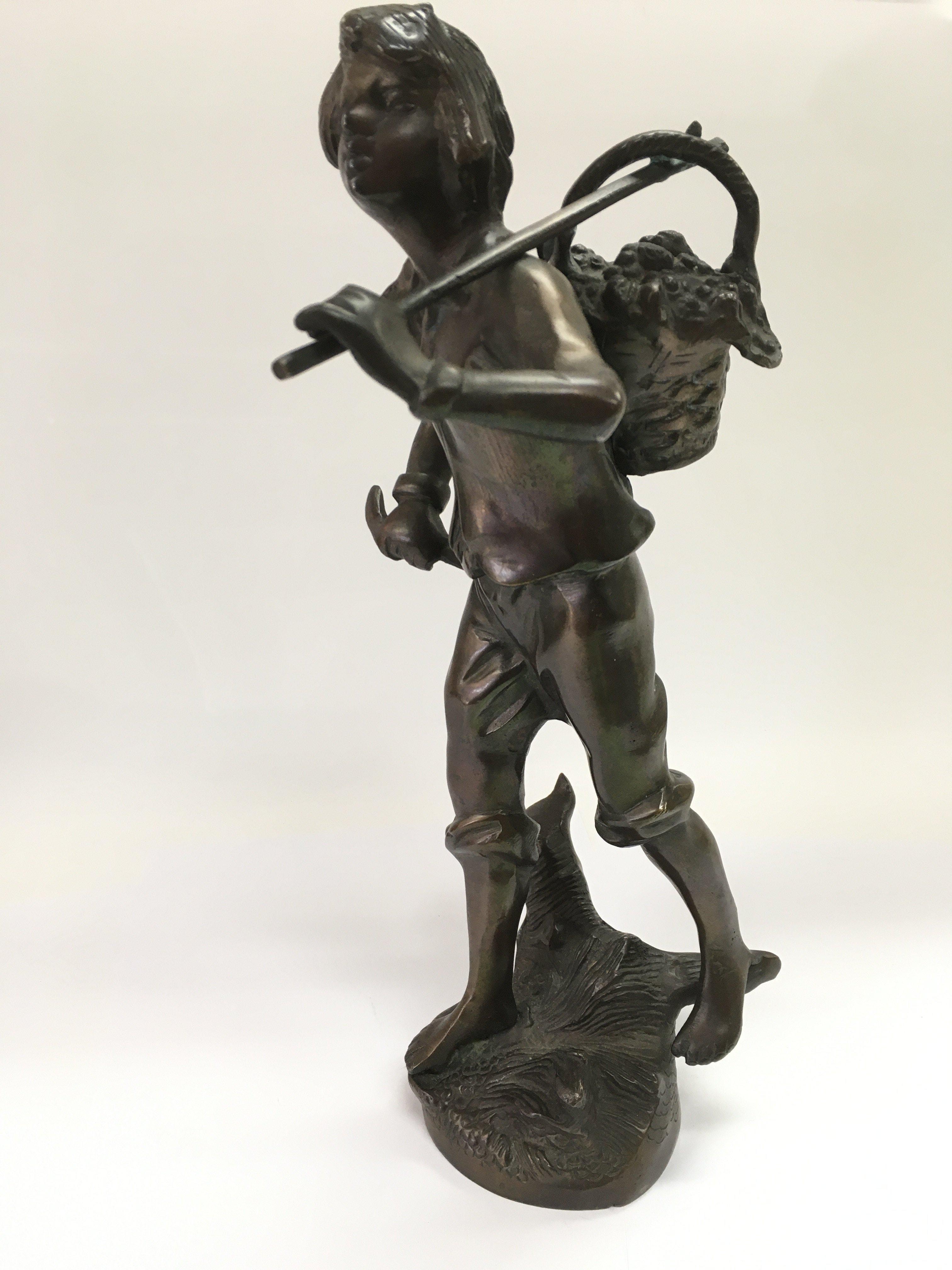 A bronze figure of a farmworker carrying a basket