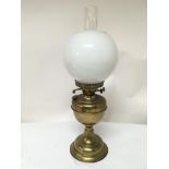 A brass oil lamp with opaque glass shade and glass