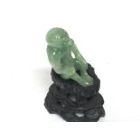 A small Chinese carved green jade monkey on a hard