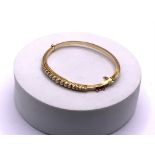 A gold bangle tested 14ct ( minimum) set with grad