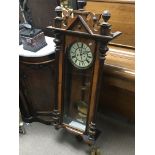 A Vienna style Continental wall clock with a visible pendulum and two brass weights