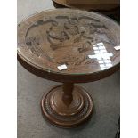 A carved hardwood Indonesian table with a carved circular top.