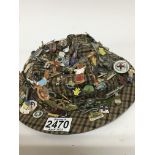 A large quantity of vintage enamel badges mounted on a hat.