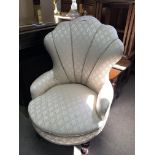 An Art Deco design cream fabric upholstered chair with turned legs terminating in brass caster