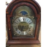 A Reproduction mahogany manual clock the arched dial with Roman numerals.