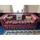 A red leather three seater button back sofa