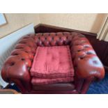 A single red leather button back club chair