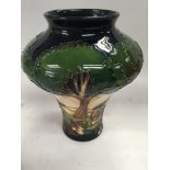 A Moorcroft vase decorated with trees within a lan