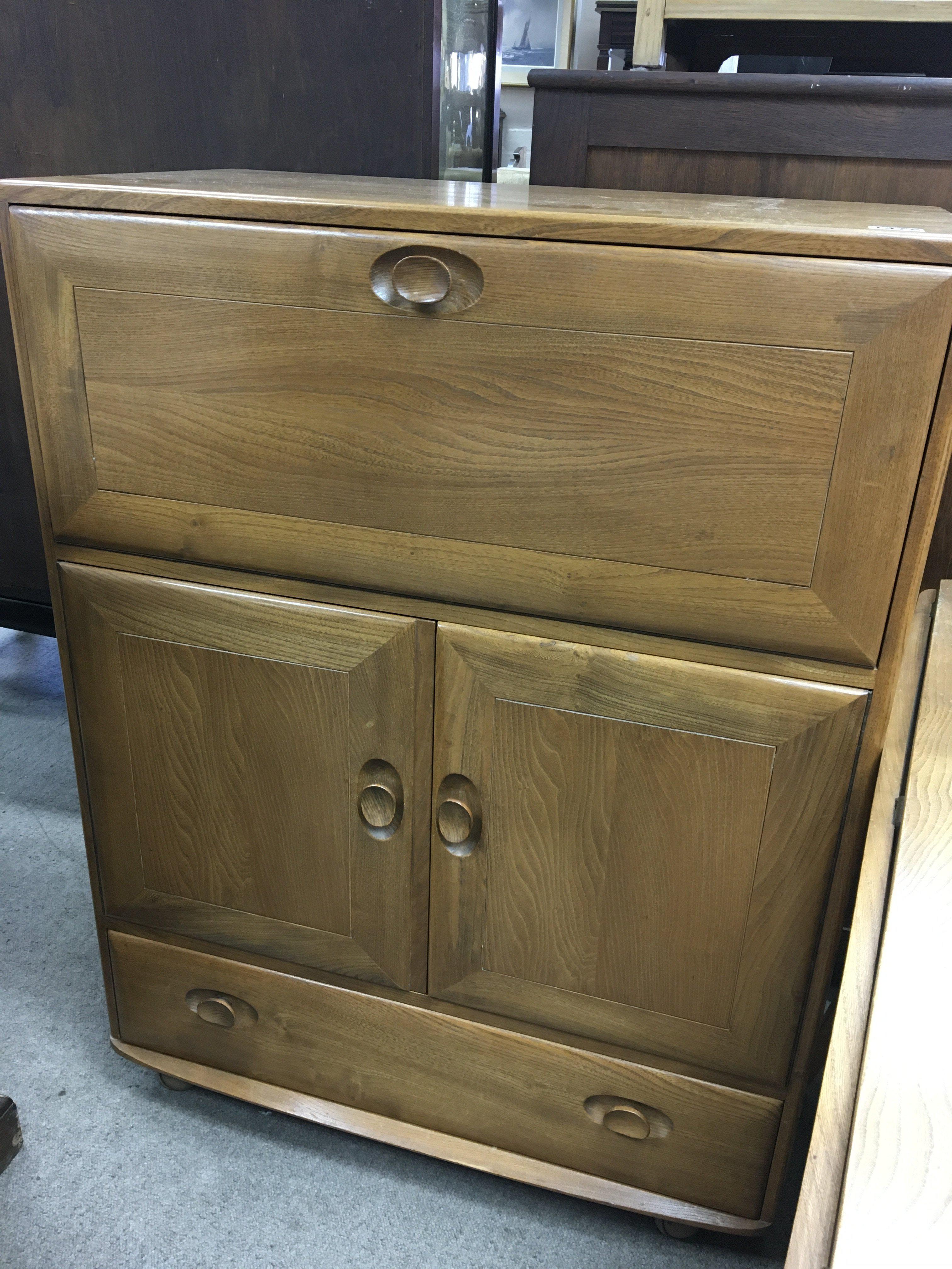 A Ercol cabinet with fall front a pair of cupboard