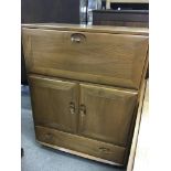 A Ercol cabinet with fall front a pair of cupboard