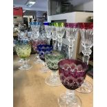 Two sets of coloured bohemian glasses .