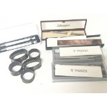 A collection of silver napkin rings and boxed pens