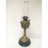 A Victorian brass oil lamp with glass chimney on a