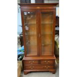 A modern glazed display cabinet with 3 draw sectio